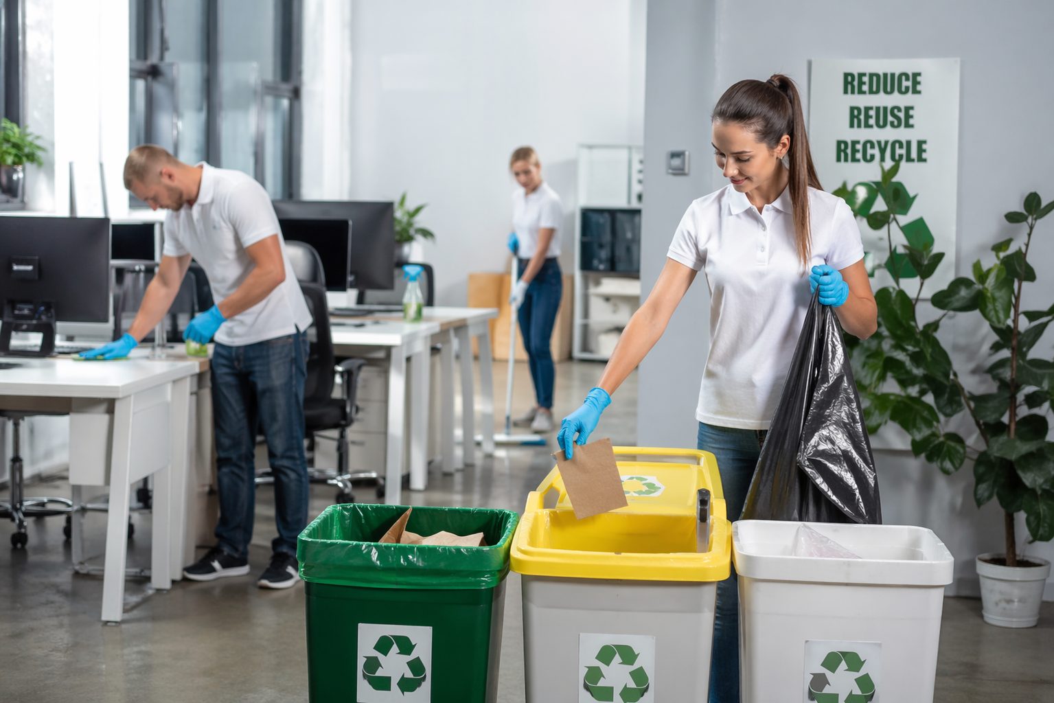 Employée en bureau moderne triant des déchets recyclables pendant un nettoyage de bureaux efficace