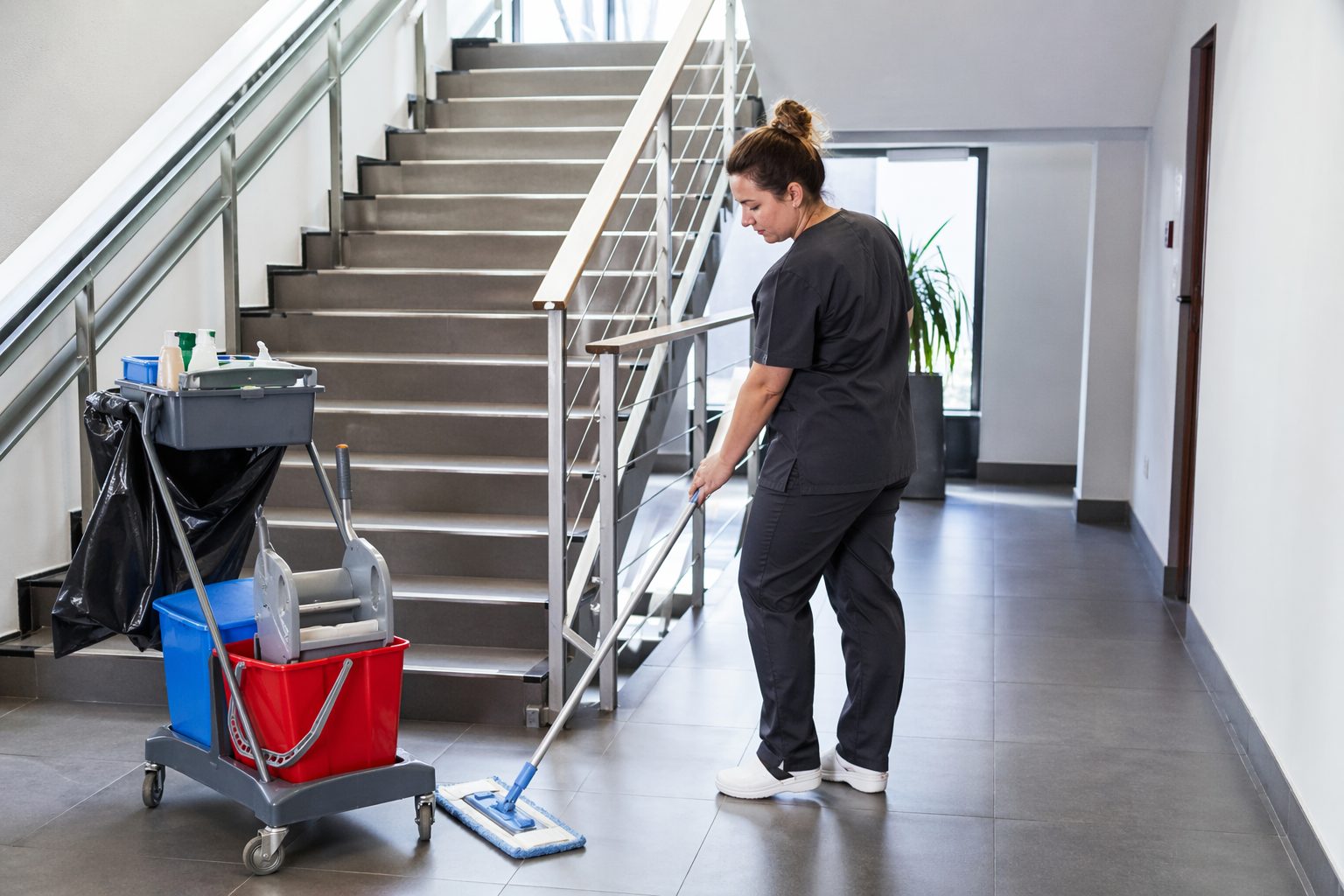 Agent d’entretien nettoyant un escalier et une circulation dans un immeuble de bureaux moderne