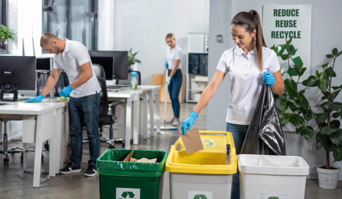 Employée en bureau moderne triant des déchets recyclables pendant un nettoyage de bureaux efficace