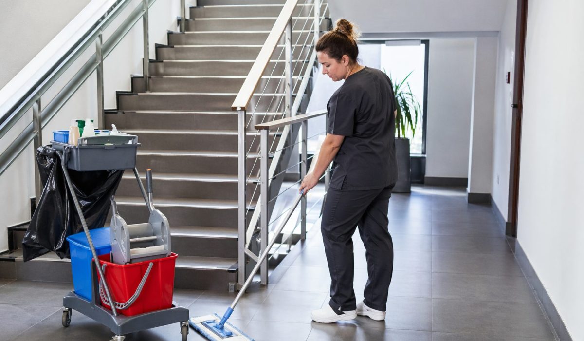 Agent d’entretien nettoyant un escalier et une circulation dans un immeuble de bureaux moderne